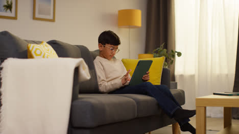 Der-Kleine-Junge-Sitzt-Zu-Hause-Auf-Dem-Sofa-Und-Spielt-Spiele-Oder-Streamt-Inhalte-Auf-Sein-Digitales-Tablet-2